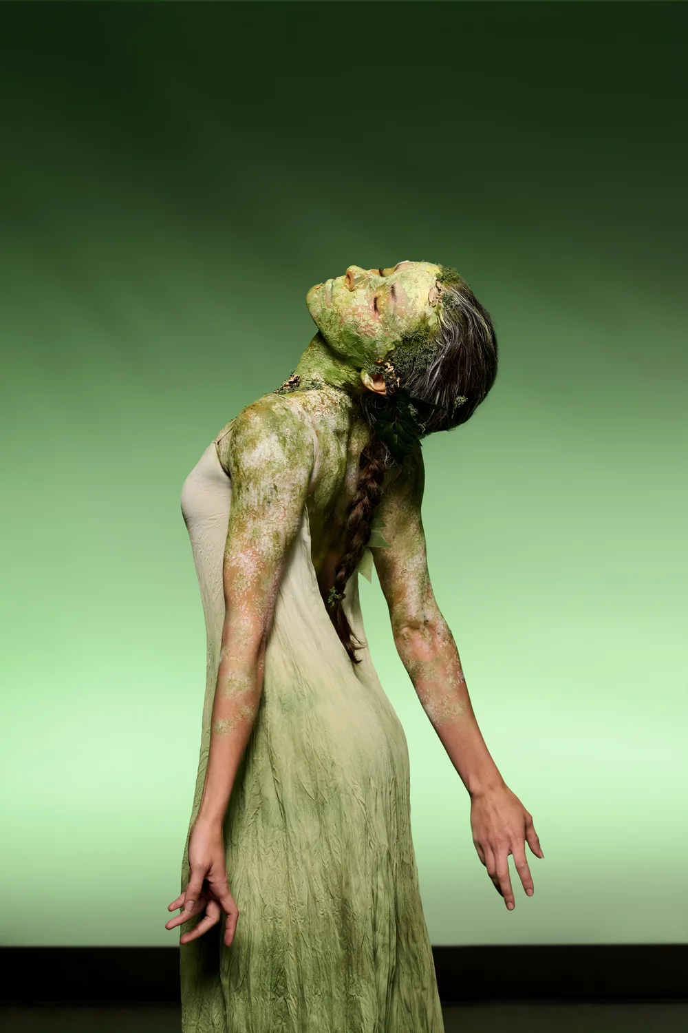 A moss-green body art character leaning backward